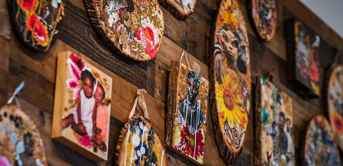 Portraits of people done on small wooden boards hang from the gallery wall.